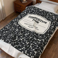 Composition Book Cover plush throw blanket with black marble notebook pattern and white label, spread across a bed