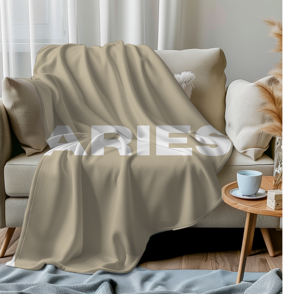 Sand-colored custom zodiac throw blanket with Aries lettering, draped over a beige sofa in a living room