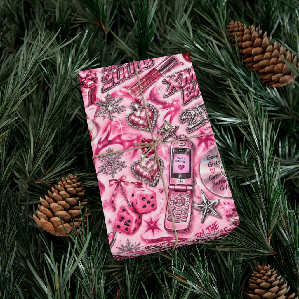 Xmas Baby Y2K Christmas wrapping paper on a pink gift box, with chrome-style hearts, stars, dice and a flip phone illustration